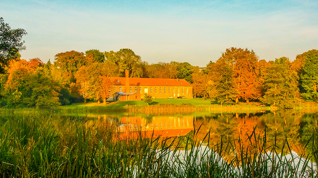 Der Marstall spiegelt sich in der herbstlichen Nachmittagssonne im Schlossteich